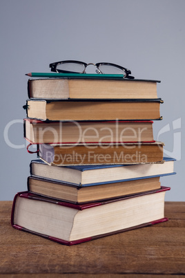 Spectacles and pencil on book stack
