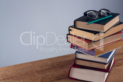 Spectacles and pencil on book stack