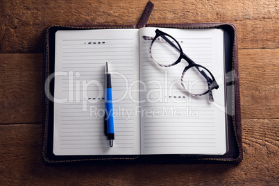 Spectacles and pen on organizer at desk
