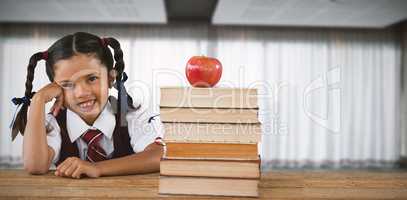 Composite image of schoolgirl leaning by books and apple on desk