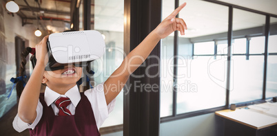 Composite image of school girl pointing while using vr headset