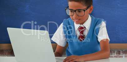 Composite image of schoolboy using laptop at table