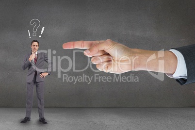 Hand pointing at business man against grey background with question and exclamation marks