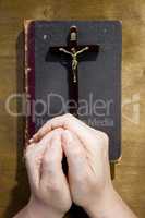 Hands with a crucifix and an old book