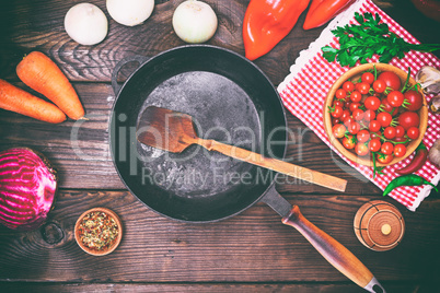 Empty black frying pan with fresh vegetables