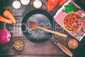 Empty black frying pan with fresh vegetables