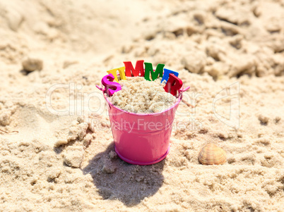 Pink baby bucket with sand and inscription summer