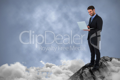 Composite image of businessman standing while using laptop computer