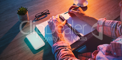 Cropped hands of businessman writing in diary