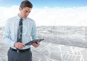 Businessman using tablet in sea of documents under sky clouds