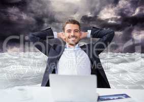 Businessman on laptop in sea of documents under dark sky clouds