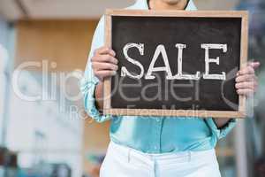 Business woman holding a blackboard with sale text