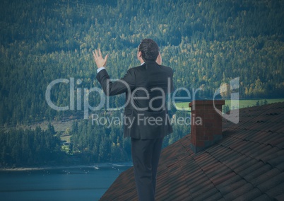 Businessman standing on Roof with chimney and forest mountain