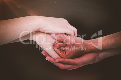 Composite image of cropped hands holding together