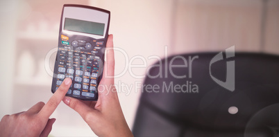 Composite image of hands of businesswoman using calculator