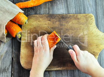 Two female hands with a knife and carrot