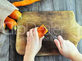 Two female hands with a knife and carrot