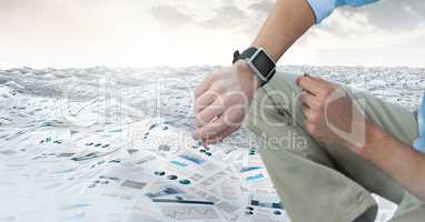 Businessman in sea of documents under sky clouds with watch