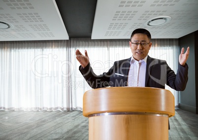 Businessman on podium speaking at conference with windows