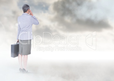 Businesswoman under sky clouds with briefcase