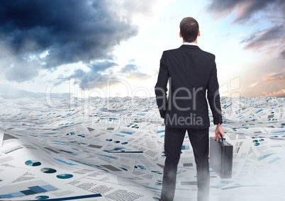Businessman holding briefcase in sea of documents under sky clouds opening