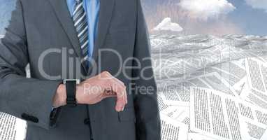 Businessman with watch in sea of documents under sky clouds