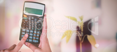 Composite image of hands of businesswoman using calculator