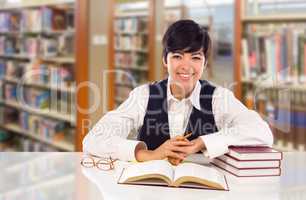 Young Female Mixed Race Student In Library with Books, Paper and