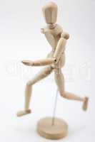 A wooden mannequin running and looking at us.