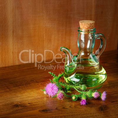 Oil and flowers of milk thistle on wooden