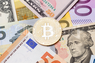 Golden bitcoin coin on us and euro notes.
