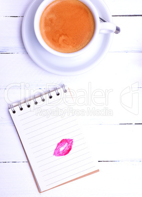 Empty notepad with a lipstick print and a cappuccino