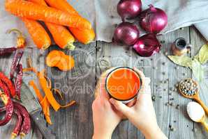 Female hands holding carrot juice in an iron mug
