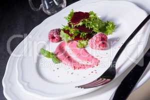 Carpaccio of baked red pray with green salad and raspberry