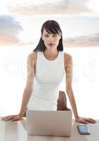Businesswoman on laptop under sky clouds