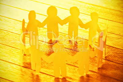 Yellow paper figures forming circle on wooden table