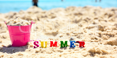 multicolored wooden letters in the word summer on sand
