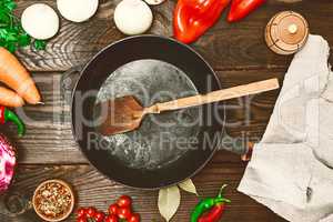 empty black cast-iron frying pan with a wooden spoon