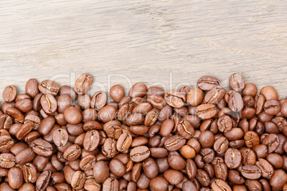 Coffee beans on the brown wooden background.