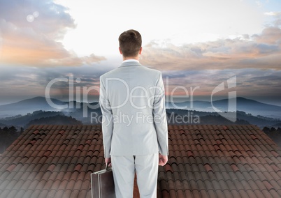 Businessman standing on Roof with chimney and misty landscape