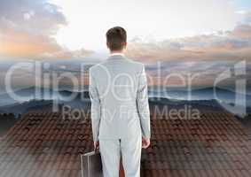 Businessman standing on Roof with chimney and misty landscape