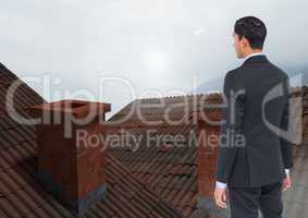 Businessman standing on Roofs with chimney and fog