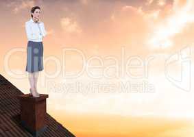 Businesswoman on roof chimney with golden sky