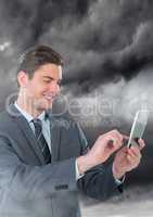Businessman on phone in front of dark cloudy sky