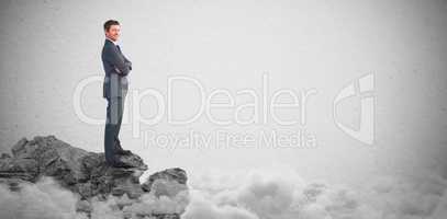 Composite image of businessman standing with arms crossed
