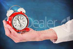 Composite image of cropped hand holding alarm clock