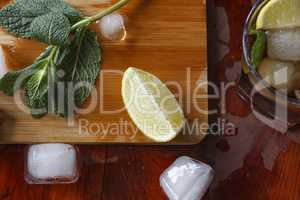 Ingredients for an alcoholic cocktail: ice, mint, lemon, lime. Rum, whiskey, cognac