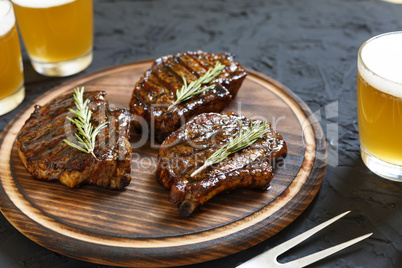 Very delicious steak BBQ and beer in glasses on a black stone background