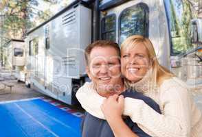 Happy Caucasian Couple In Front of Their Beautiful RV At The Cam