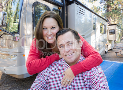 Happy Caucasian Couple In Front of Their Beautiful RV At The Cam